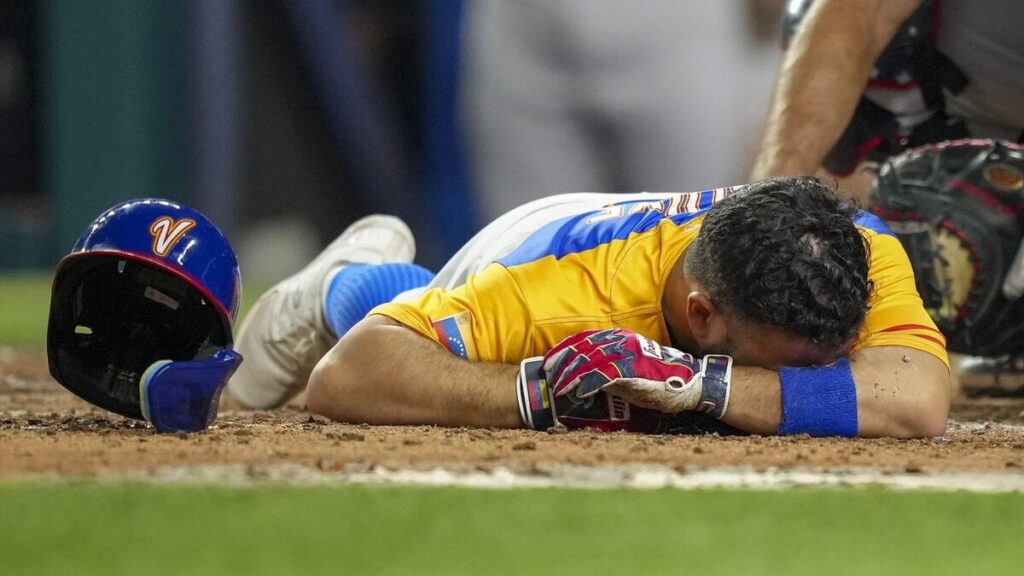 Jose Altuve falls to the ground after getting hit by a pitch on his thumb at the World Baseball Classic