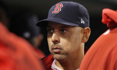 Alex Cora stands in the dugout during a Boston Red Sox game.