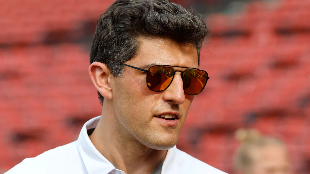 Chaim Bloom wears red sunglasses while standing in Fenway Park before a day game.