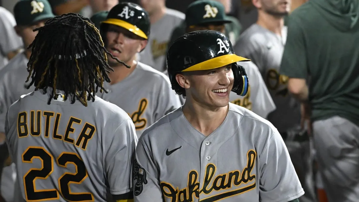 Zack Gelof smiles in the dugout after hitting a home run for the Oakland A's on the road.