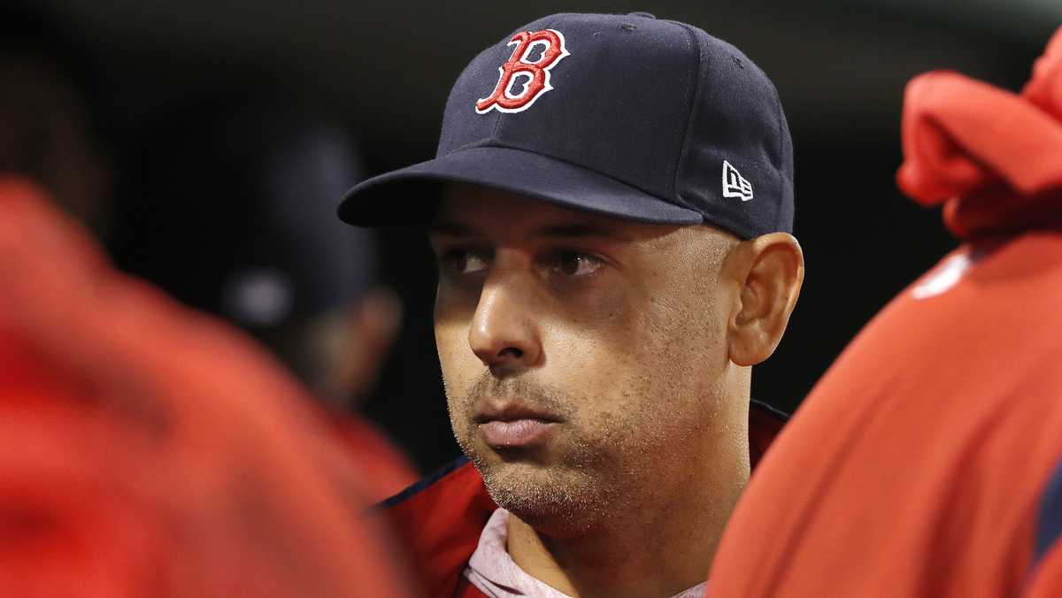 Alex Cora stands in the dugout during a Boston Red Sox game.