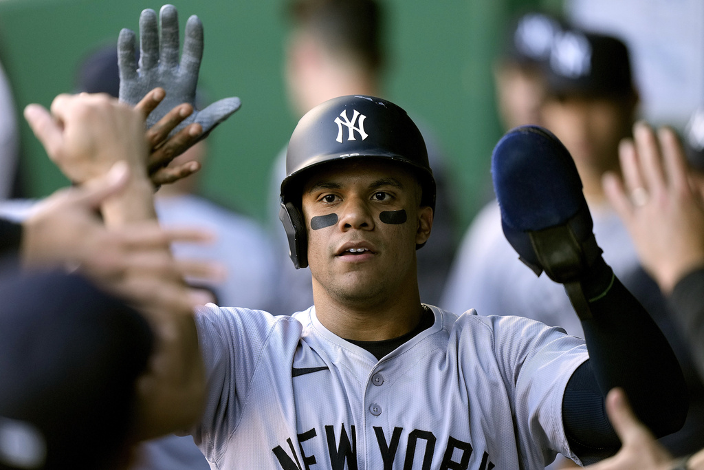 Juan Soto high-fives his teammates in the New York Yankees dugout.