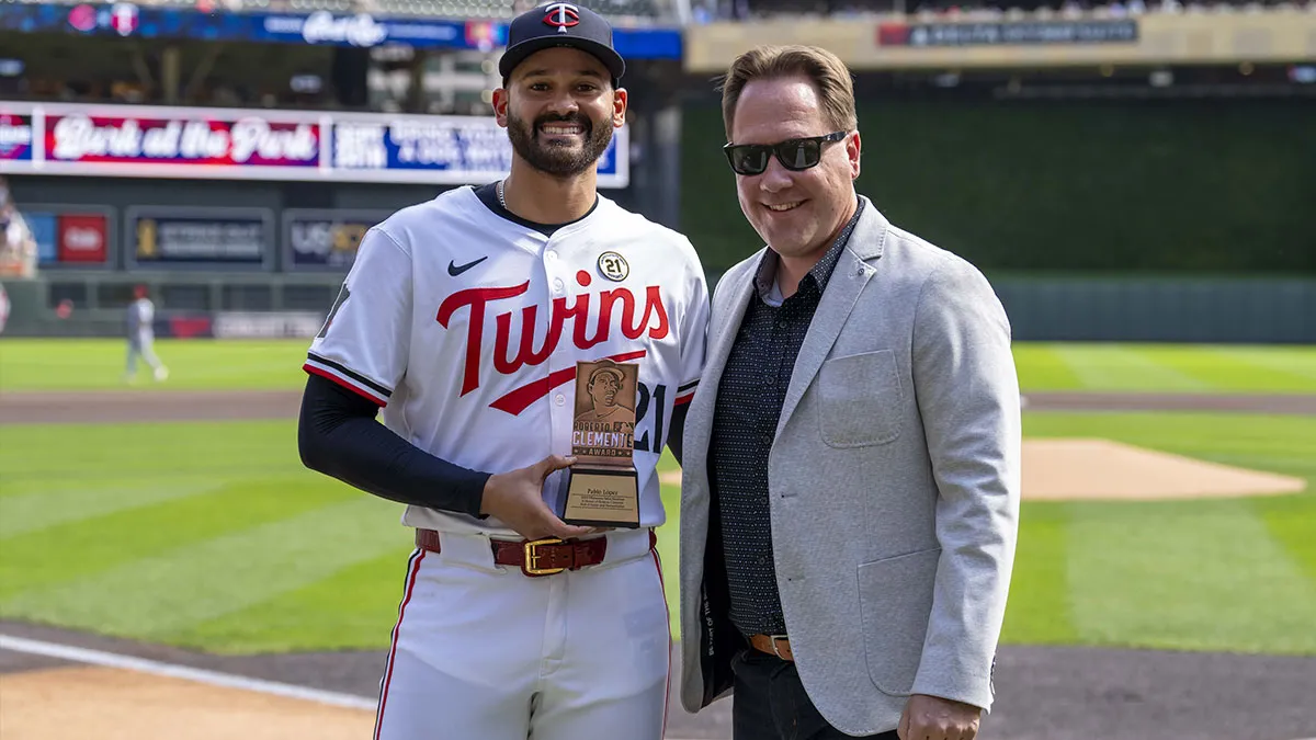 Derek Falvey poses on the field with Pablo Lopez, who is receiving the Roberto Clemente Award.