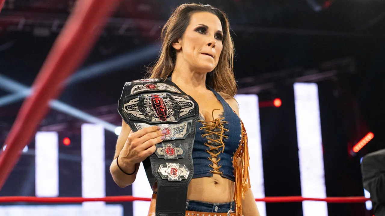 Mickie James is in the ring with a championship.